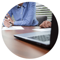 Business man writing down notes in meeting with a computer 