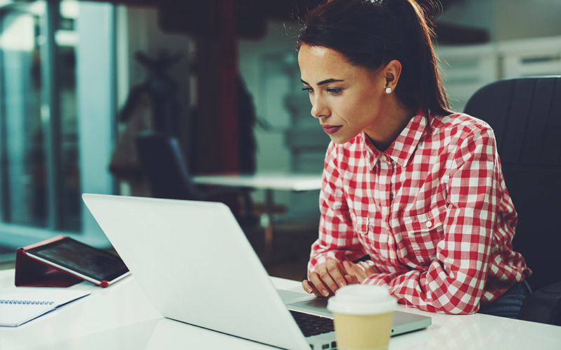 woman working on a laptop with a cup of coffee