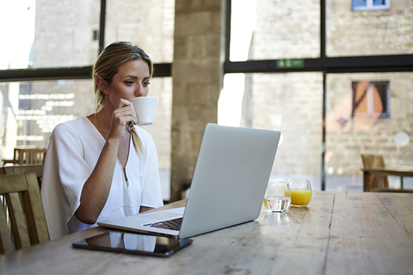 Working remotely woman while sipping coffee