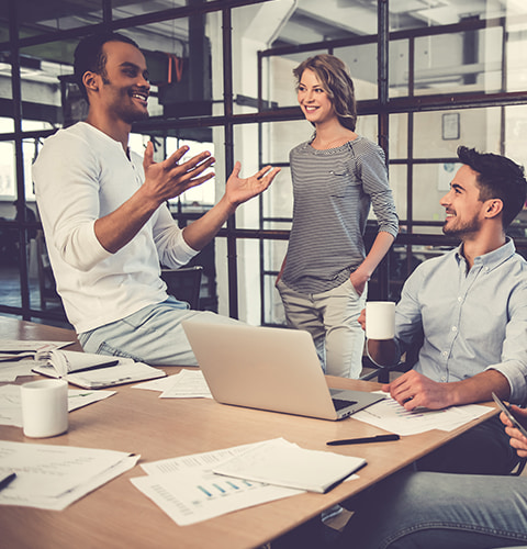 Man sat on desk talking to his colleagues