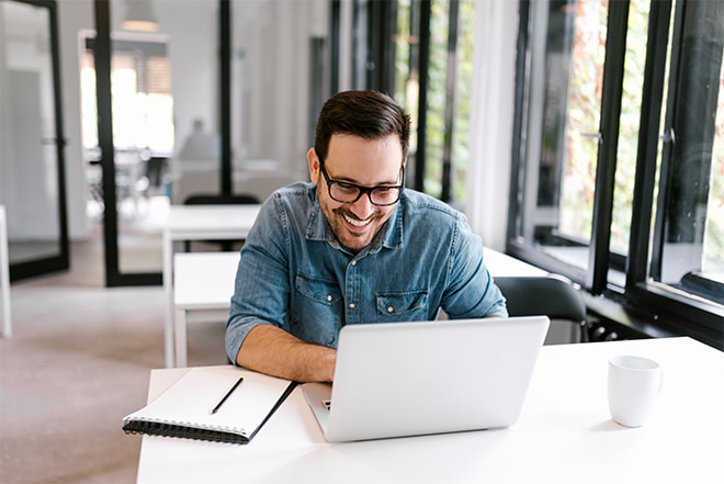 Man smiling while working on a laptop