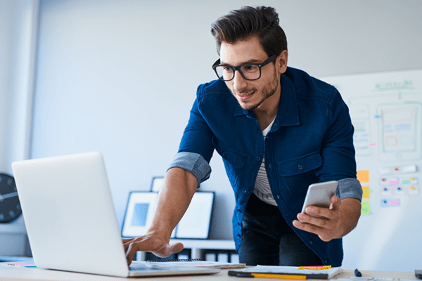 Man using laptop and cell phone for site discovery in modern workforce