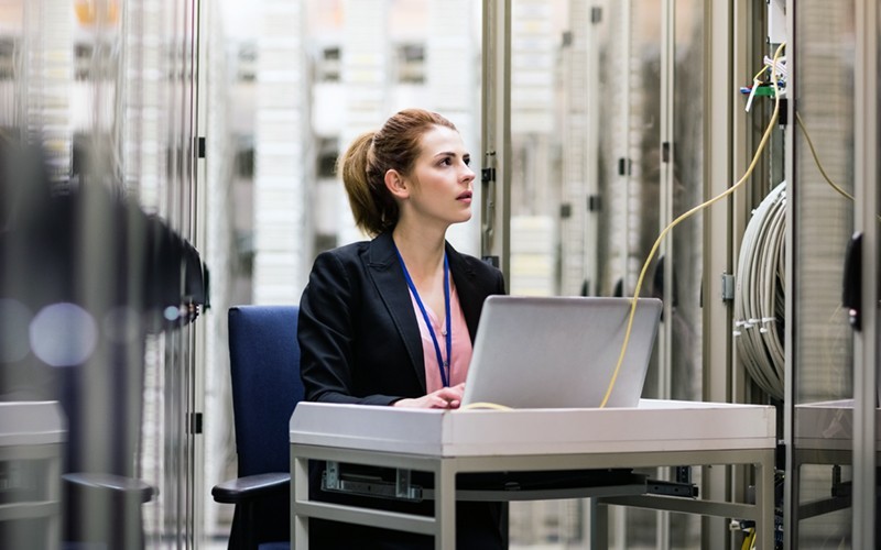 Woman working at a small desk attached to a data center