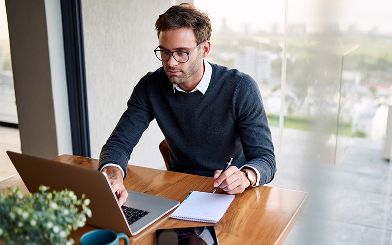 Man working on a laptop with a tablet on the table.